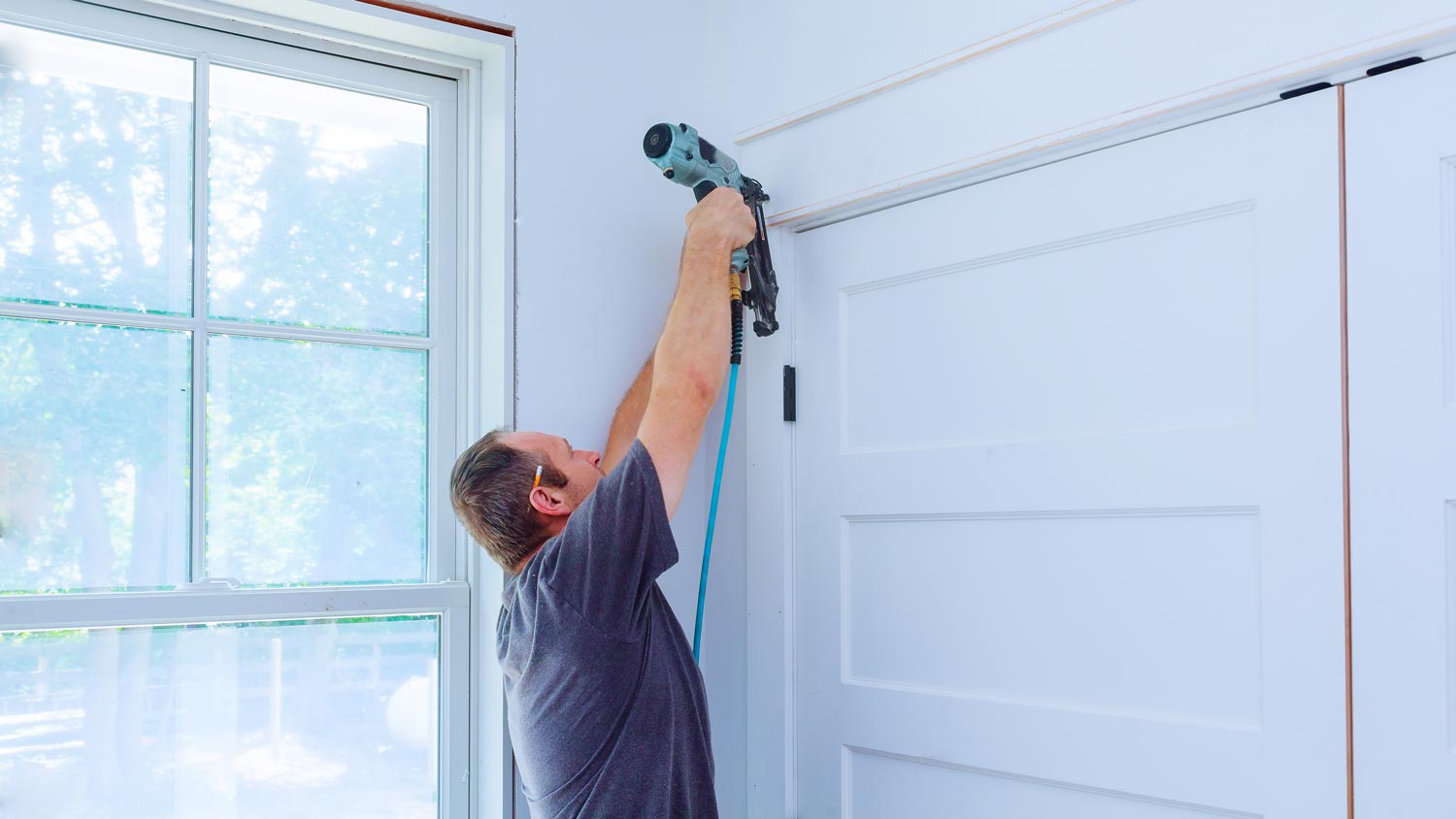 A carpenter attaching the trim to a doorway